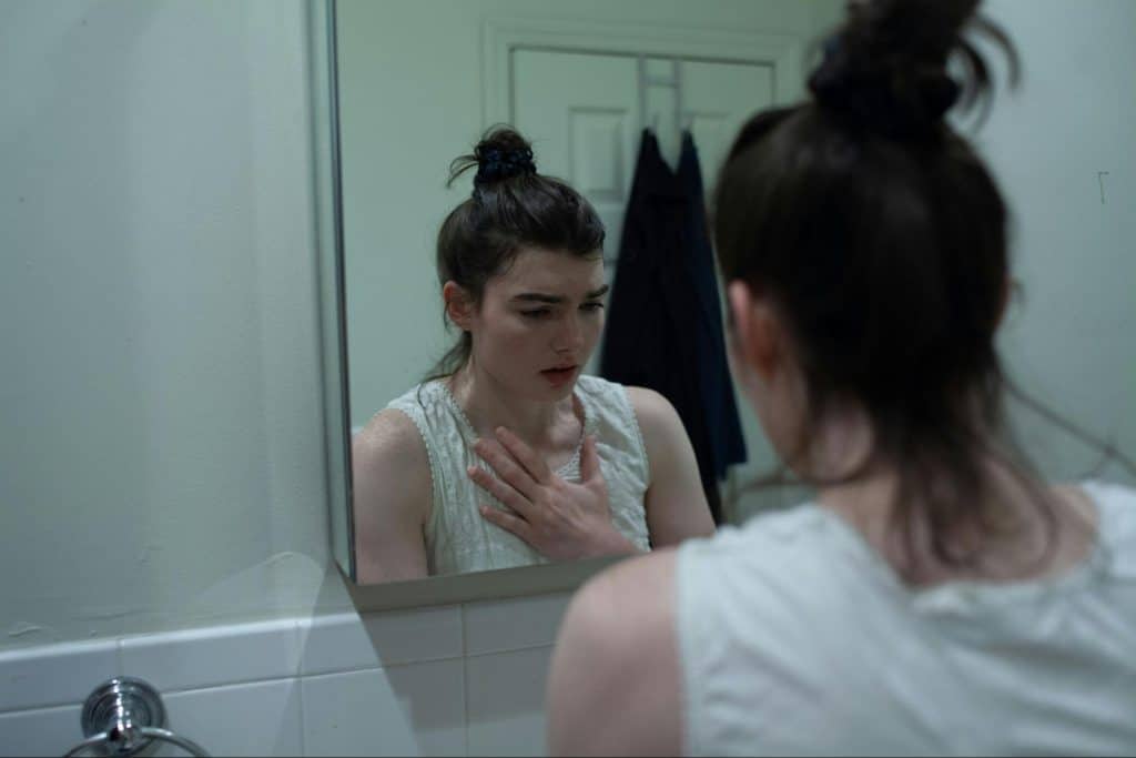 A picture of a sad woman looking at the mirror