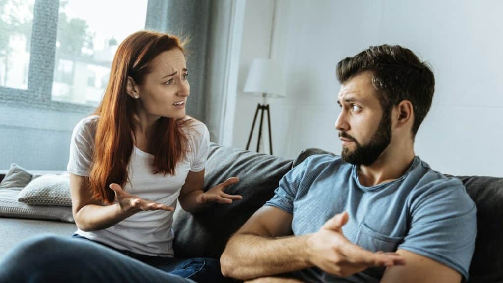 An unhappy woman looking at an indifferent boyfriend.
