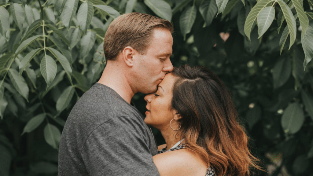 A man giving his wife a forehead kiss