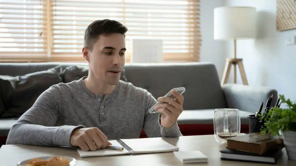 Man sitting on the floor in the living room and talking on a smartphone.