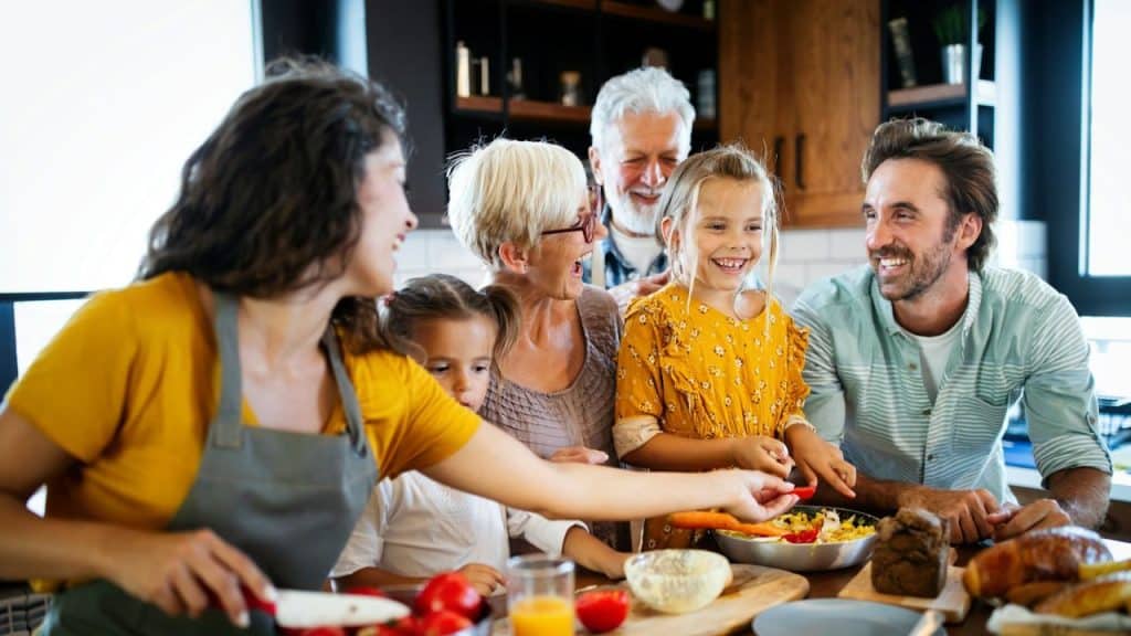 Happy extended family preparing food together in a modern kitchen setting.