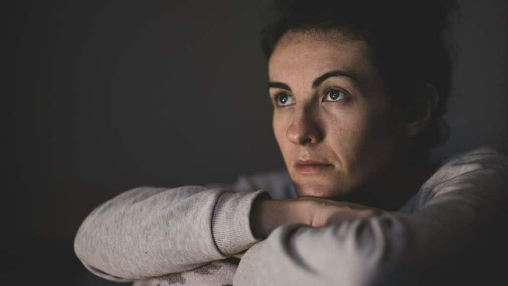 A woman resting her chin on her arms looking thoughtful.