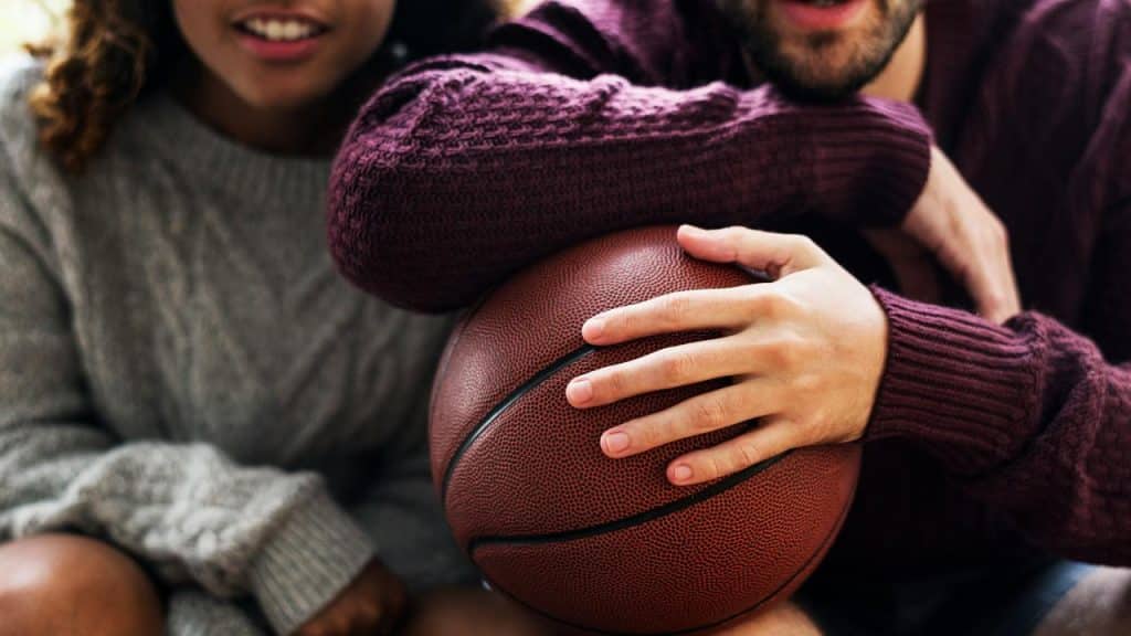 A close-up of two people sitting together, one holding a basketball while they talk.