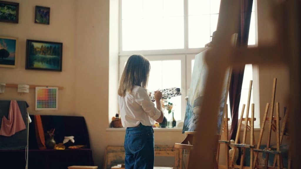 A woman painting on a canvas in a bright art studio.