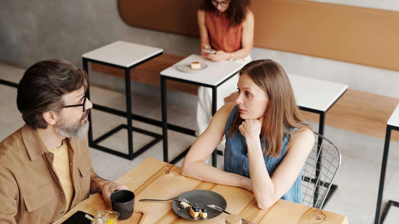 A man and a woman having a serious conversation inside a food establishment.