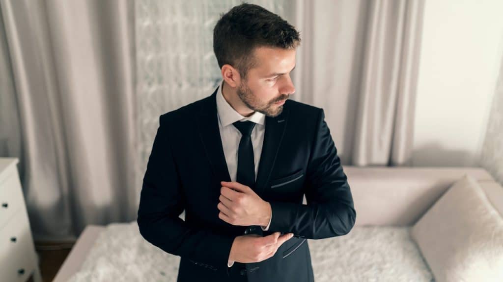 A man wearing a suit standing in a living room.