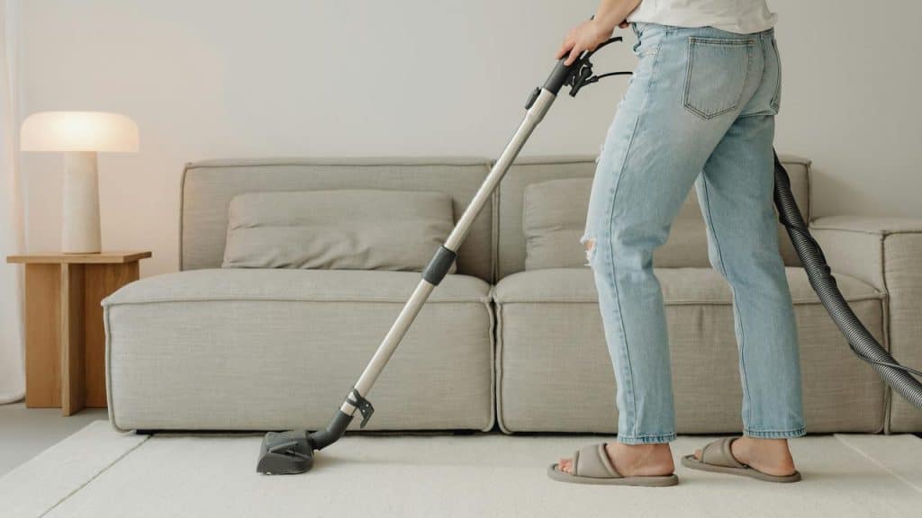 A person vacuuming a carpet in a living room.