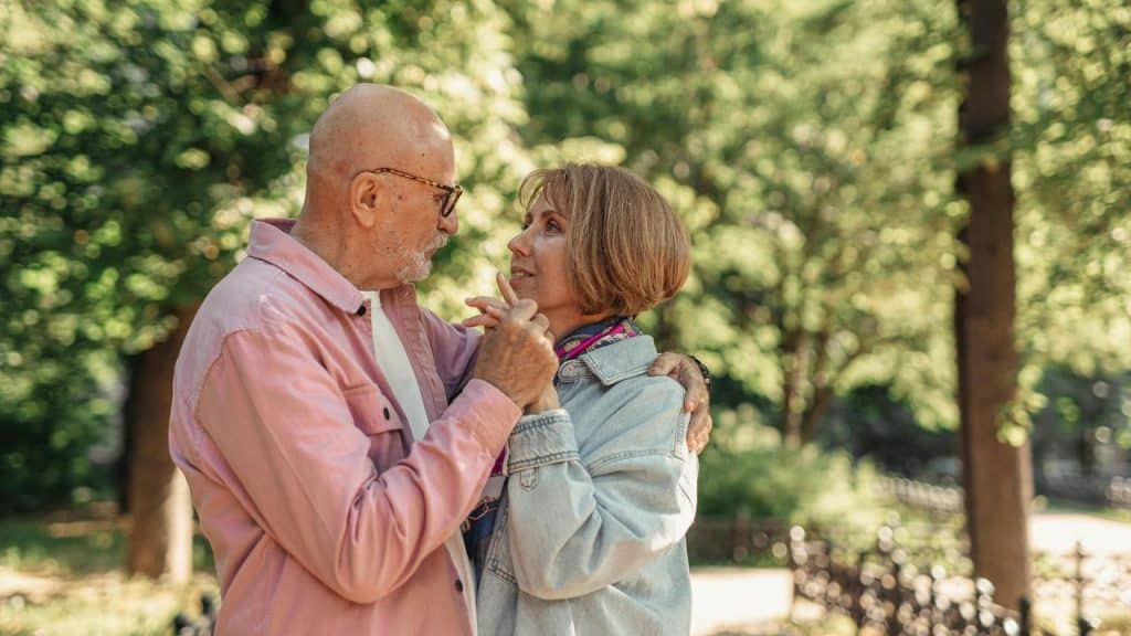 A couple standing close together and dancing outdoors.