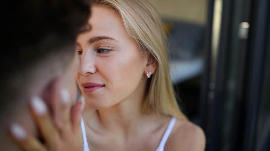 A woman gently touching the face of her boyfriend.