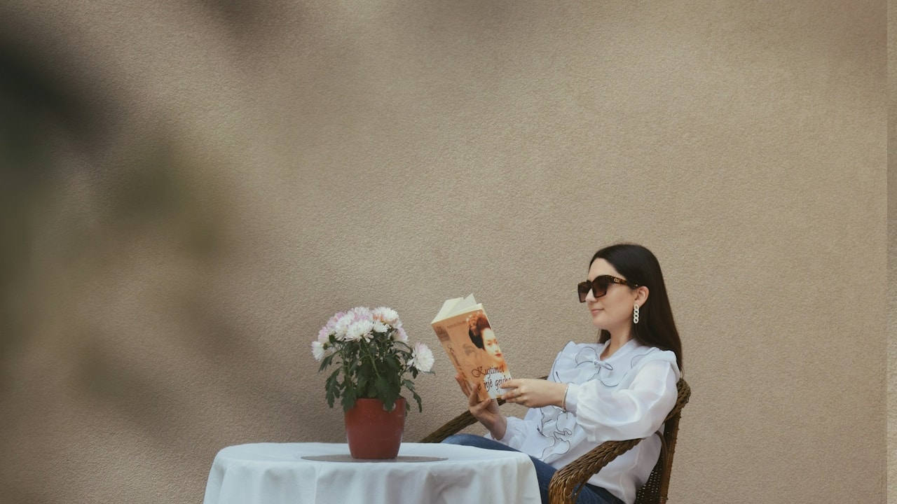 A woman reading a book while sitting at a table.