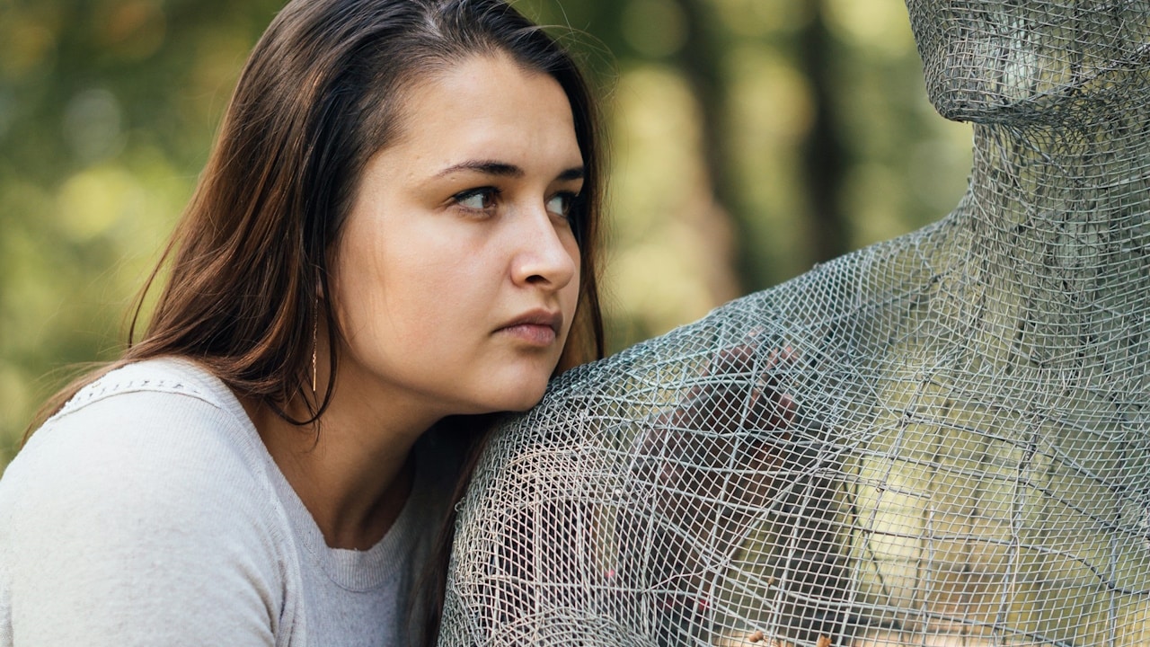 A woman leaning on a sculpture made up of net.