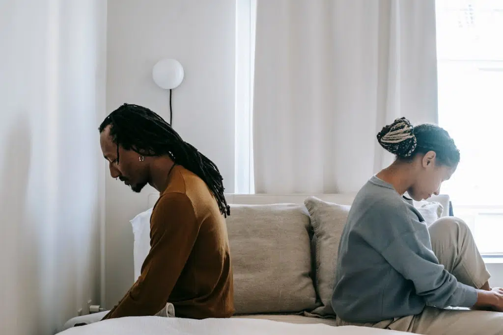 Concerned black couple sitting on bed in misunderstanding