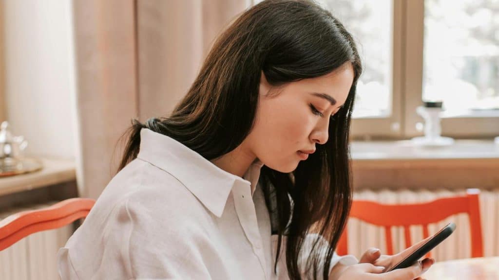 A young woman looking down at her phone indoors.