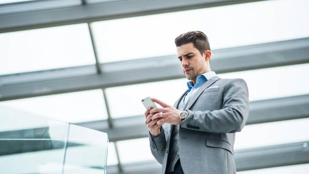 A man in a suit looking at his smartphone.