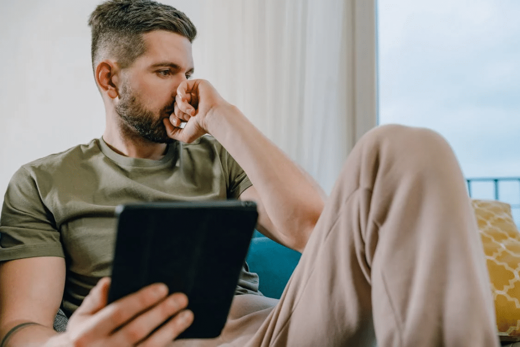 Man Sitting on Sofa Holding a Computer Tablet