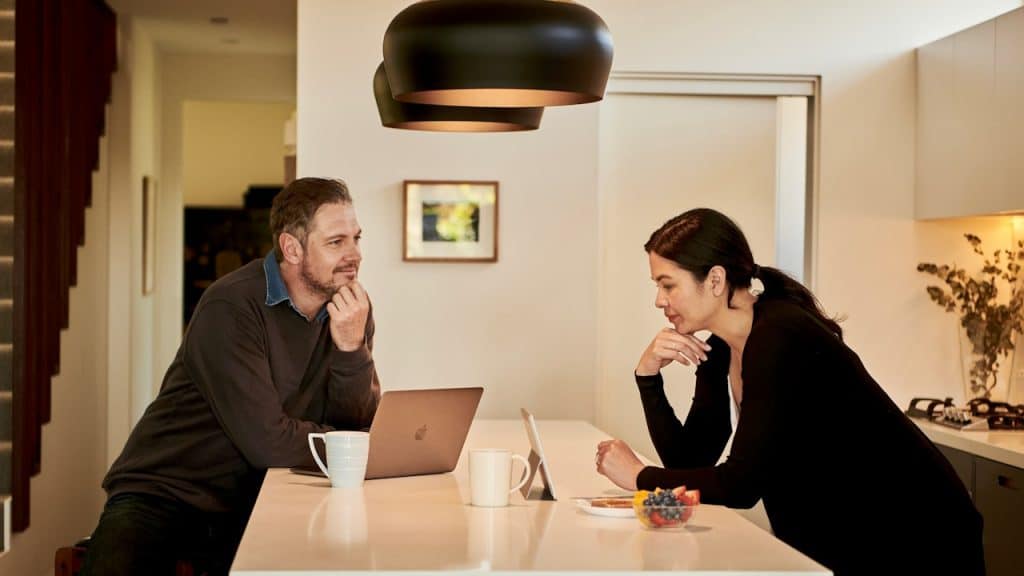 A man and a woman sitting at a table with a laptop and a smartphone.