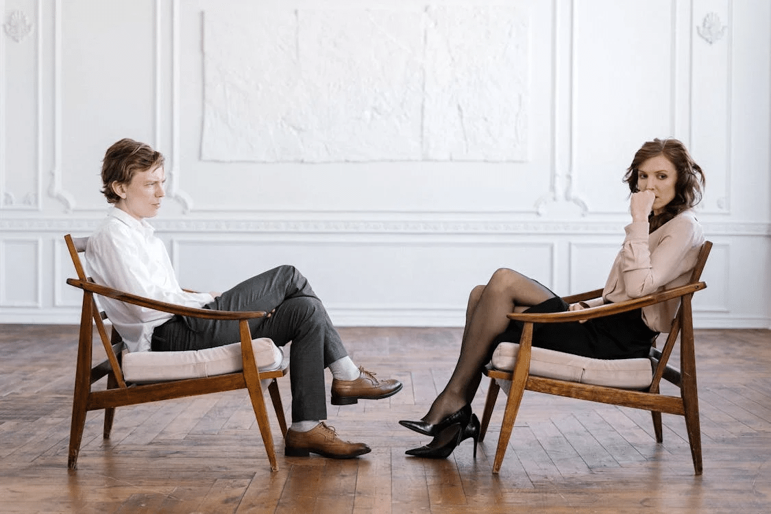 Woman in white long sleeve shirt and gray pants sitting on brown wooden chair
