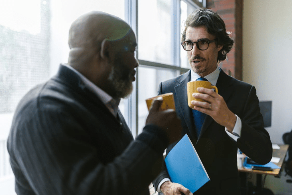 Men Having Conversation while Holding Mugs