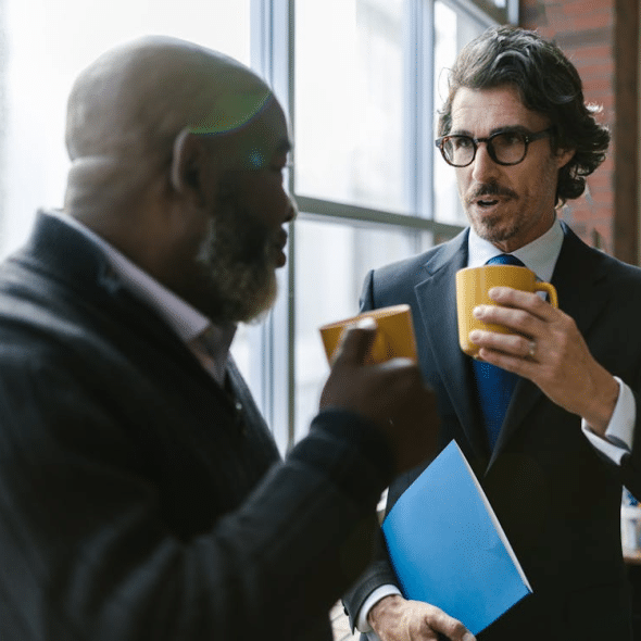 Men Having Conversation while Holding Mugs