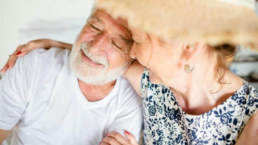 An older couple smiles and leans close together affectionately.