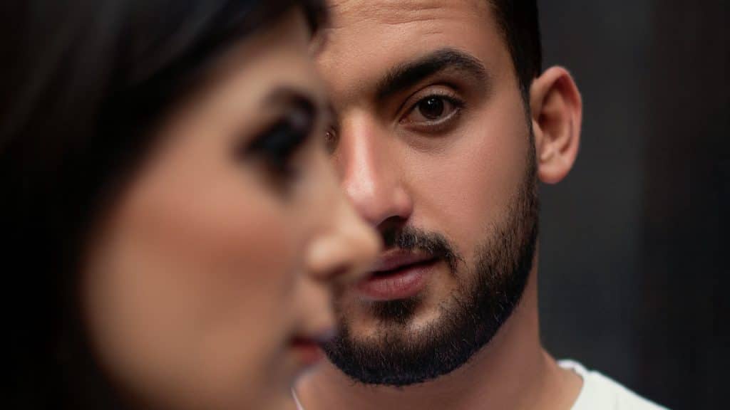 A man looking in the camera while his angry wife is looking sideways.