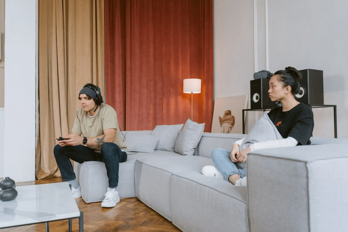 Woman looking at man playing video game