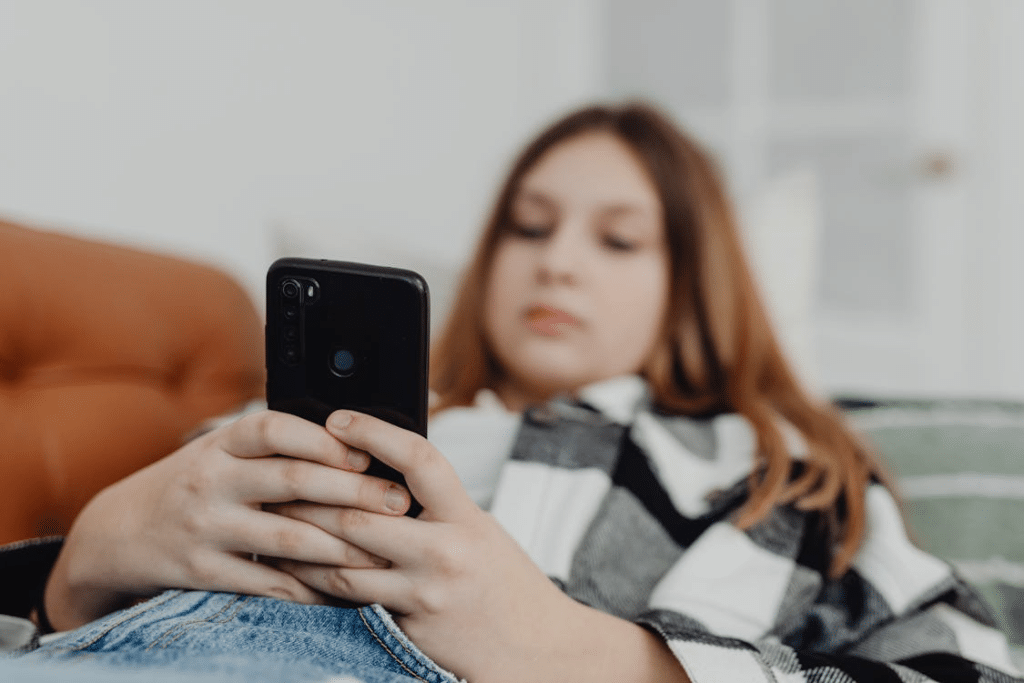 A woman lying on a sofa while using a phone