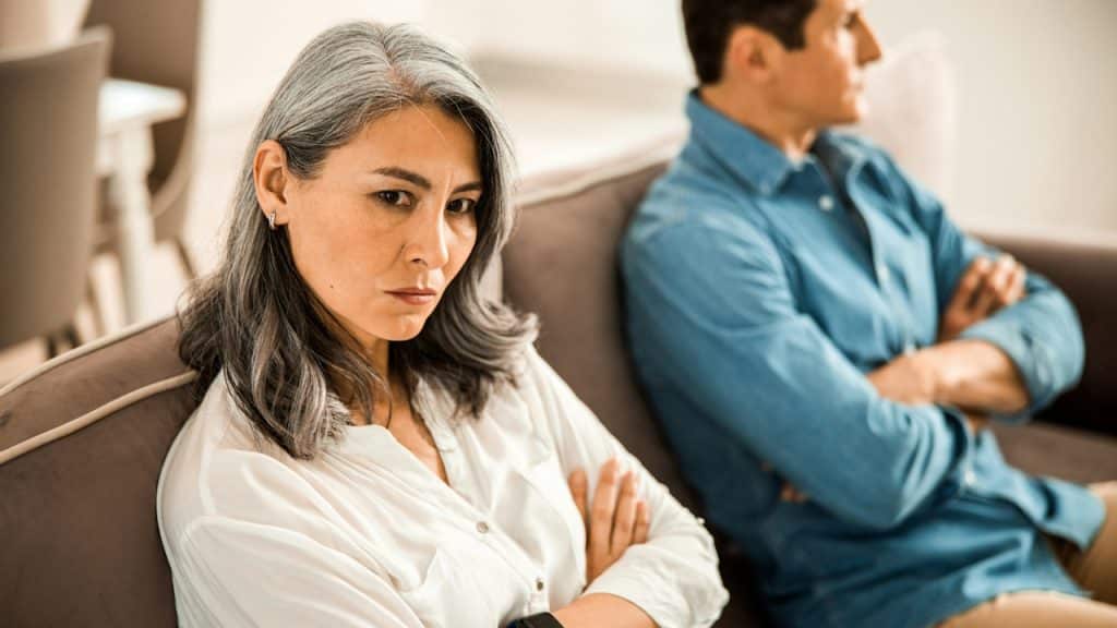 An older couple on a couch refusing to look at each other.