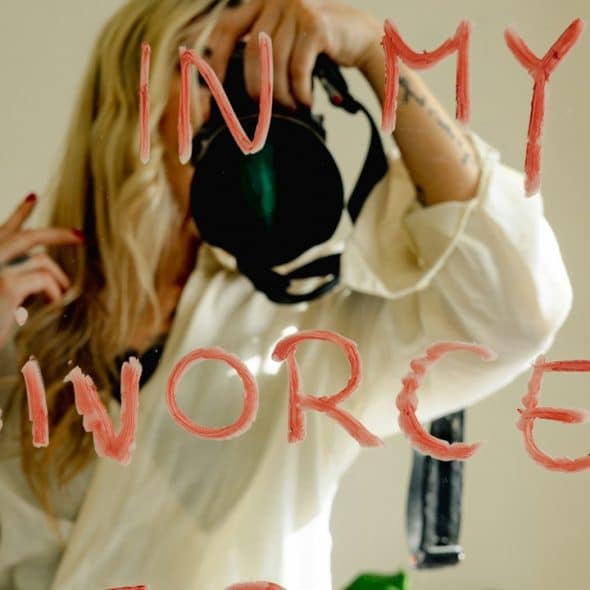 A woman takes a mirror selfie with the text "divorced era."
