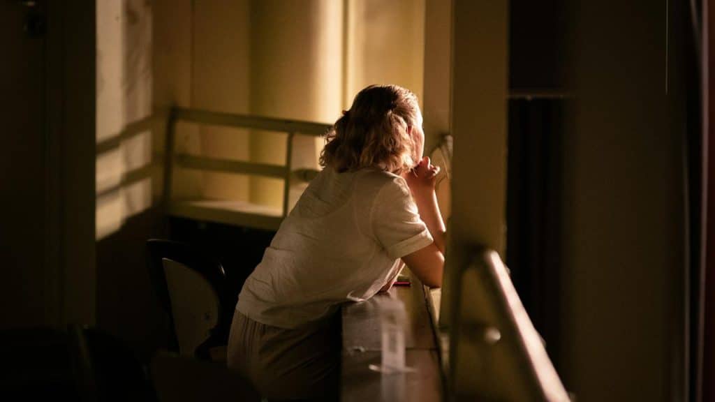 A woman leaning on a windowsill looking outside.