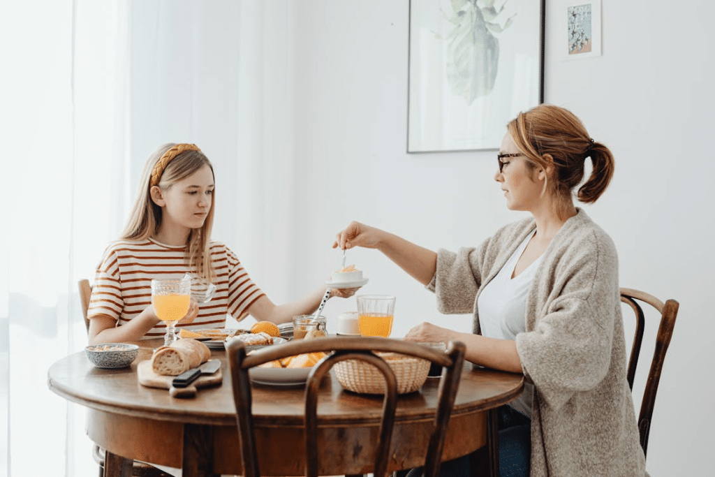 Woman and a Girl Eating Sweet Breakfast at a Wooden Table