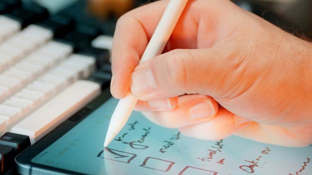 A person checking off items on a list on a tablet with a stylus pen.