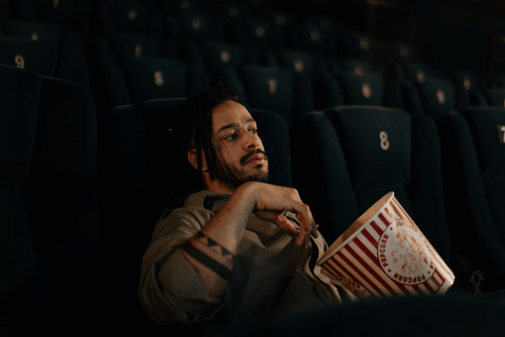 Bearded Man Sitting in the Movie Theater while Holding Popcorn