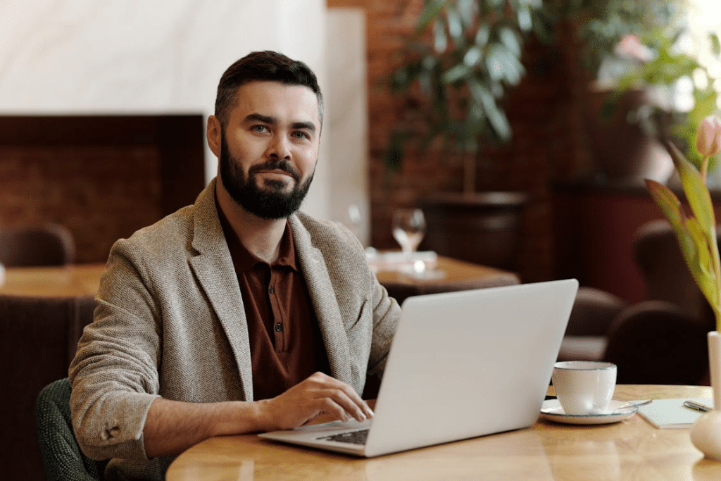 Man Sitting on a table with Laptop and Cup of Coffee