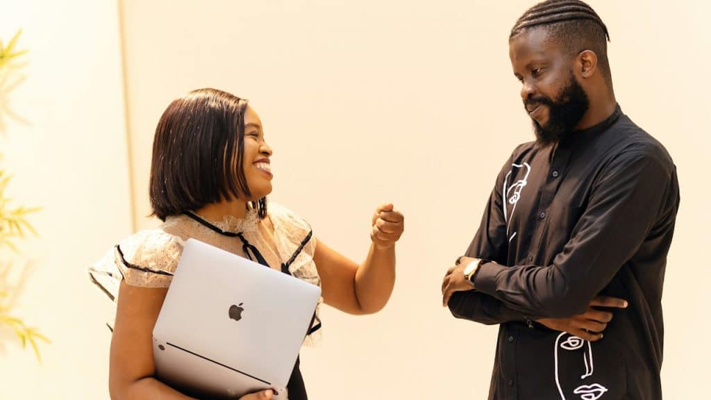 A woman with a laptop laughing at a man standing next to her.