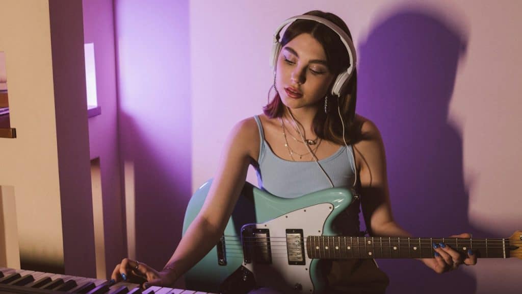 A woman with headphones playing a guitar.