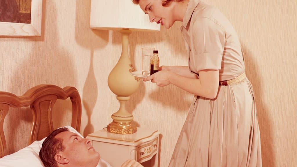 Woman carrying a tray of medicine to sick husband in bed.