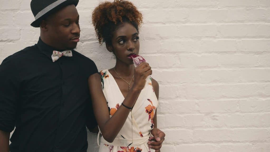 A man and a woman standing in front of a white-painted wall.