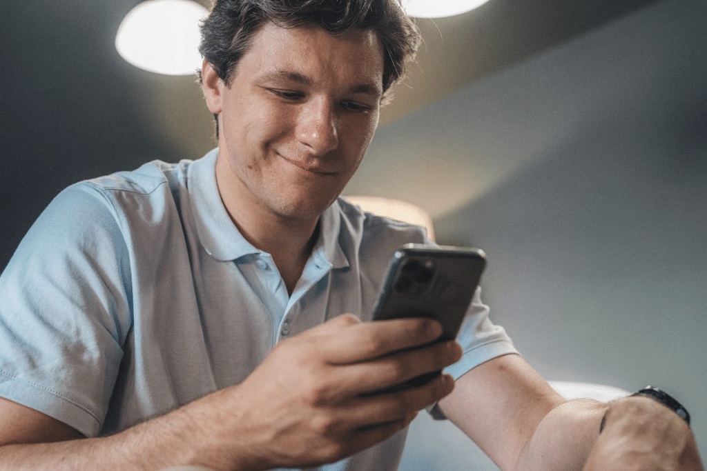 Man in Blue Polo Shirt Holding a Smartphone