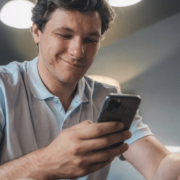Man in Blue Polo Shirt Holding a Smartphone