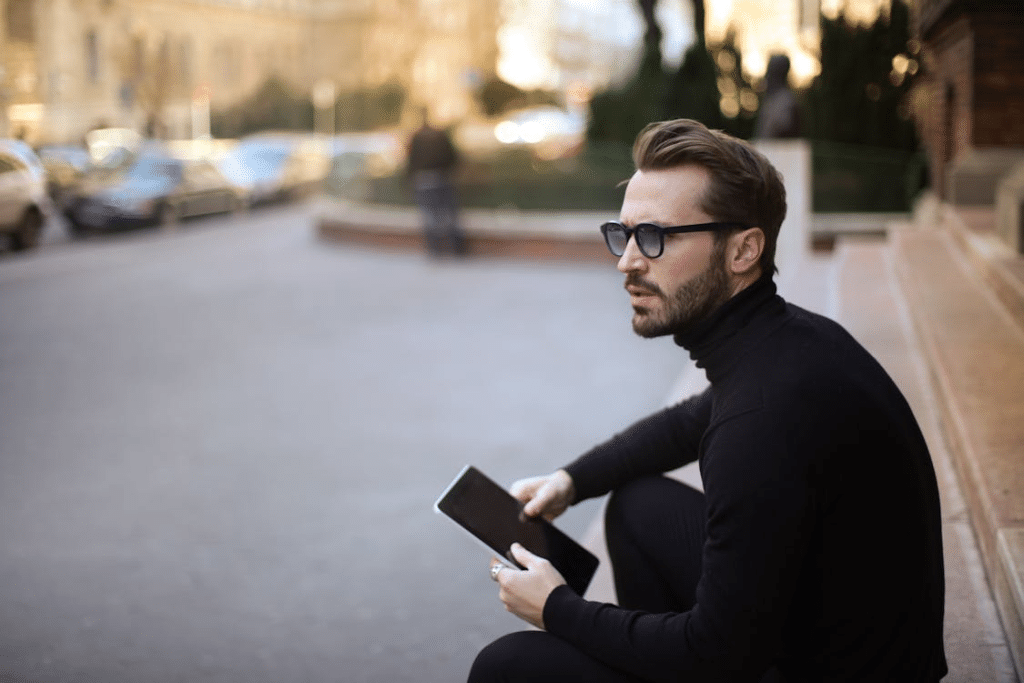 Pensive troubled stylish man with notepad on street