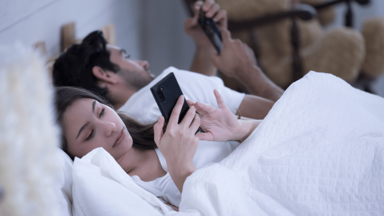 A couple using their phones before sleeping