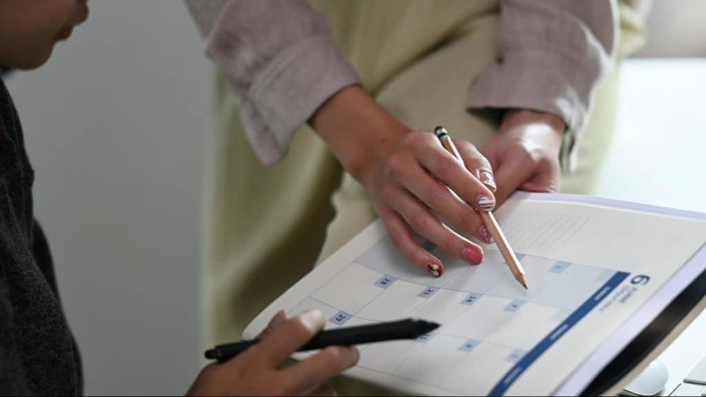 A person using a pencil to highlight a date on a calendar.