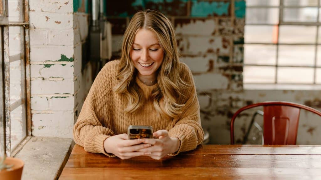 A woman sitting at a table looking at her cell phone.