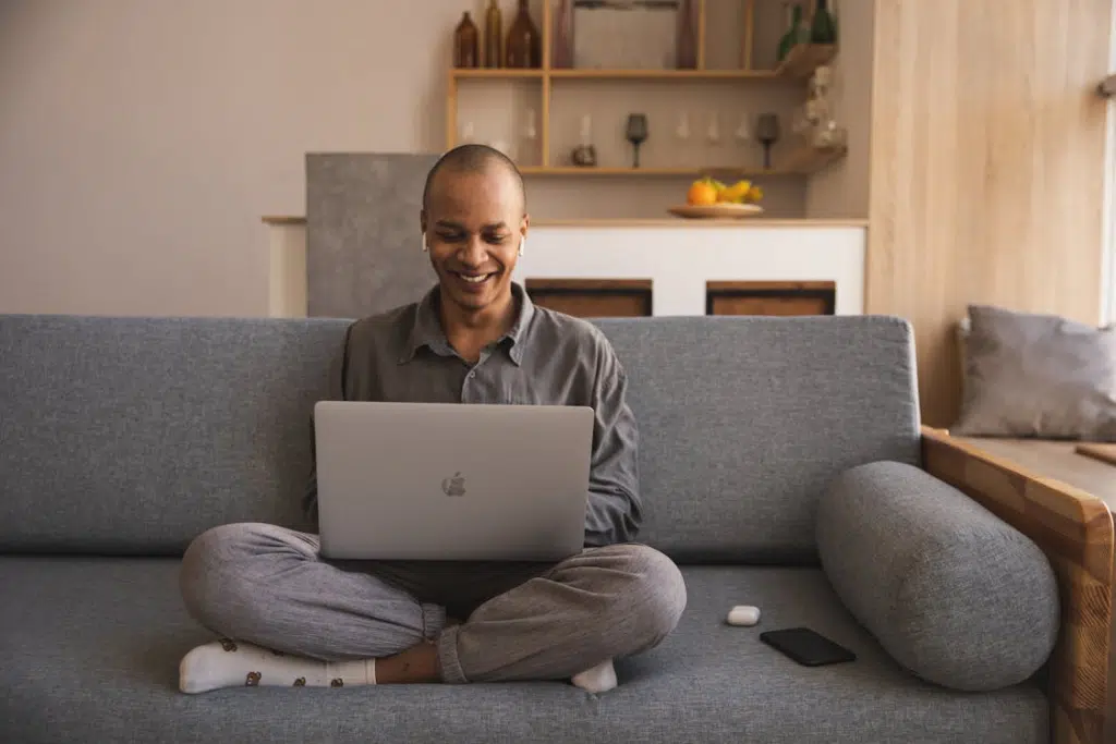 A man smiling while using a laptop