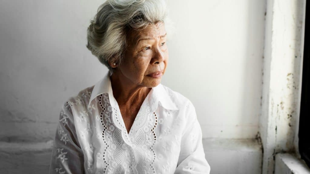 An older woman with a sad expression looking to the side.