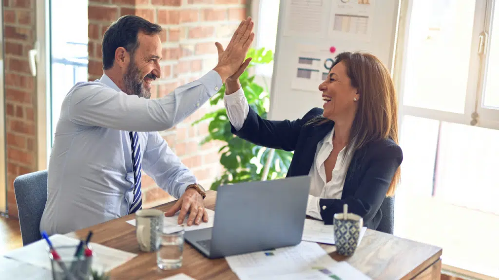 Two colleagues high fiving at work