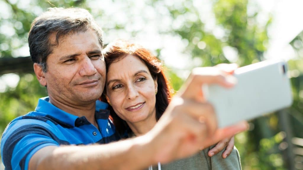 A middle-aged man and woman taking a selfie outdoors.