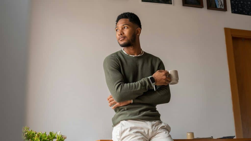 A man looking to the side while holding a coffee mug.