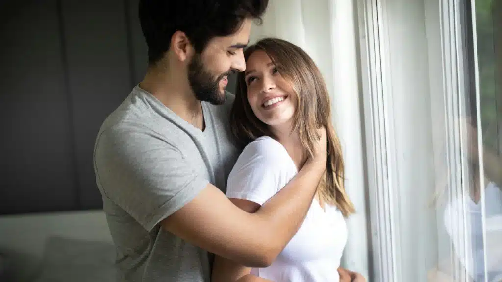 A couple hugging each other indoors.